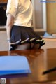 A woman in a school uniform is bending over a desk.