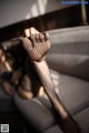 A woman in fishnet stockings is sitting on a couch.