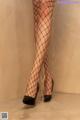 A woman in fishnet stockings and high heels standing in a shower.