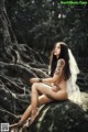 A naked woman sitting on a rock in the woods.