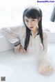 A woman in a white shirt is sitting in a bathtub.