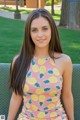 A young woman sitting on a bench in a park.