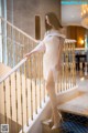 A woman in a white dress standing on a staircase.