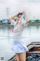 A woman in a white shirt and blue skirt posing on a boat.