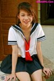 A woman in a school uniform sitting on a bench.