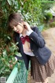 A woman in a school uniform leaning against a fence.