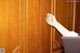 A woman's hand reaching out of a wooden cabinet.