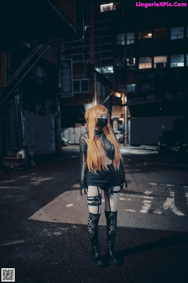 A woman wearing a face mask standing in the middle of a street.
