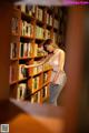 A woman standing in front of a bookshelf holding a book.