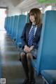 A woman in a school uniform sitting on a train.