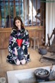 A woman in a black and red kimono sitting on the floor.