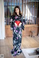 A woman in a black and purple kimono standing in front of a window.