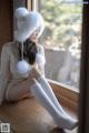 A woman sitting on a window sill wearing a white hat and socks.