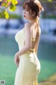 A woman in a yellow dress standing in front of a lake.