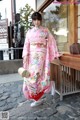 A woman in a pink kimono standing in front of a building.