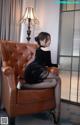 A woman sitting on a brown leather chair in a room.