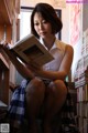 A woman sitting on a chair reading a book.