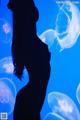 A silhouette of a woman standing in front of jellyfish.