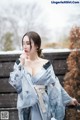 A woman in a blue kimono standing in the snow.