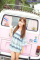 A woman standing in front of a pink and white van.