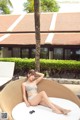 A woman in a bikini sitting on a wicker chair.