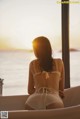 A woman sitting in a bathtub looking out the window at the ocean.