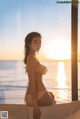 A woman in a bikini sitting on a bathtub by the ocean.