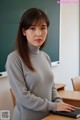 A woman standing in front of a blackboard in a classroom.