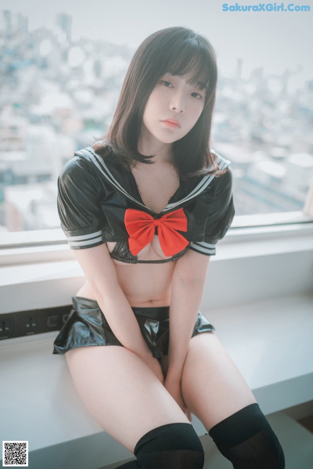 A woman in a sailor outfit sitting on a window sill.