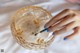 A woman's hand holding a cigarette in a glass bowl.