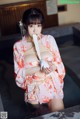 A woman in a pink kimono is tied up with a rope.