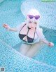 A woman in a bikini and sunglasses sitting in a pool.