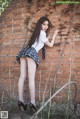 A young woman leaning against a brick wall.