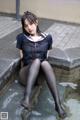 A woman in a school uniform sitting on a ledge.