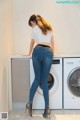 A woman standing in front of a washing machine.