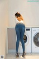 A woman standing in front of a washing machine.