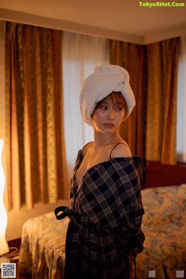 A woman with a towel wrapped around her head standing in a hotel room.