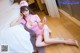 A woman in a pink nurse outfit sitting on a bed.