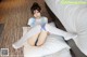 A woman sitting on top of a bed wearing white stockings.