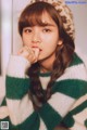 A woman wearing a green and white striped sweater and a leopard hat.