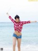 A woman standing on a beach with her arms outstretched.