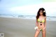 A woman in a bikini standing on a beach.