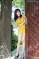 A woman in a yellow top and shorts leaning against a door.