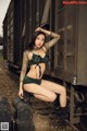 A woman in a green bikini sitting on a train track.