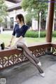 A woman sitting on a wooden bench in a park.