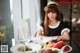 A woman sitting at a table with a plate of food and a glass of wine.