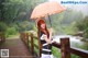 A woman standing on a wooden bridge holding an umbrella.