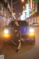 A woman sitting on the hood of a blue car.