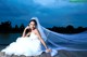 A woman in a wedding dress sitting on a dock.