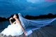 A woman in a wedding dress sitting on a dock.